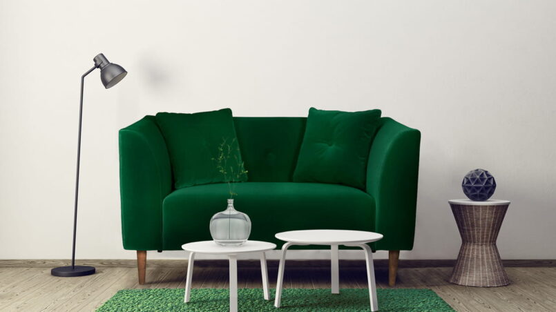 Zielona sofa dwuosobowa stoi w salonie